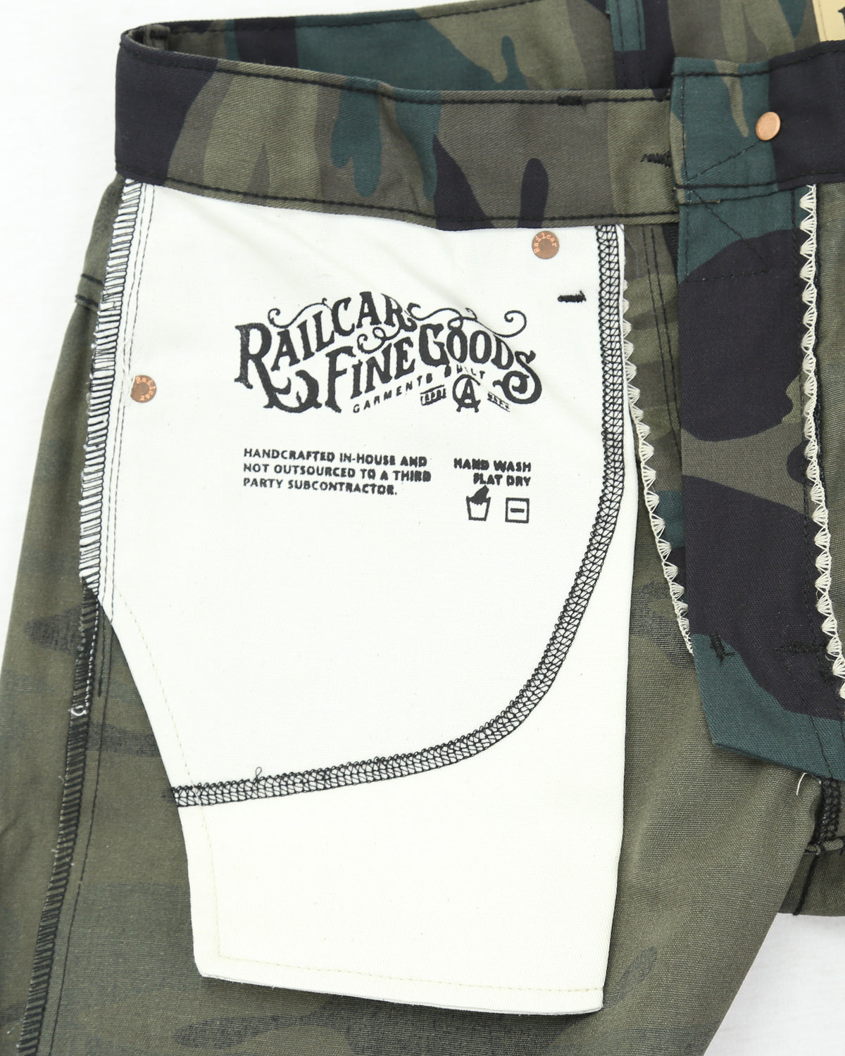Camouflage pants with a white label displaying text and branding.