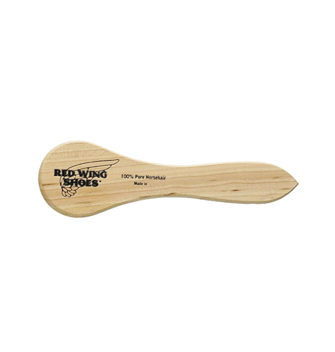 Back of a wooden mini boot brush featuring the Red Wing Heritage logo on the top.