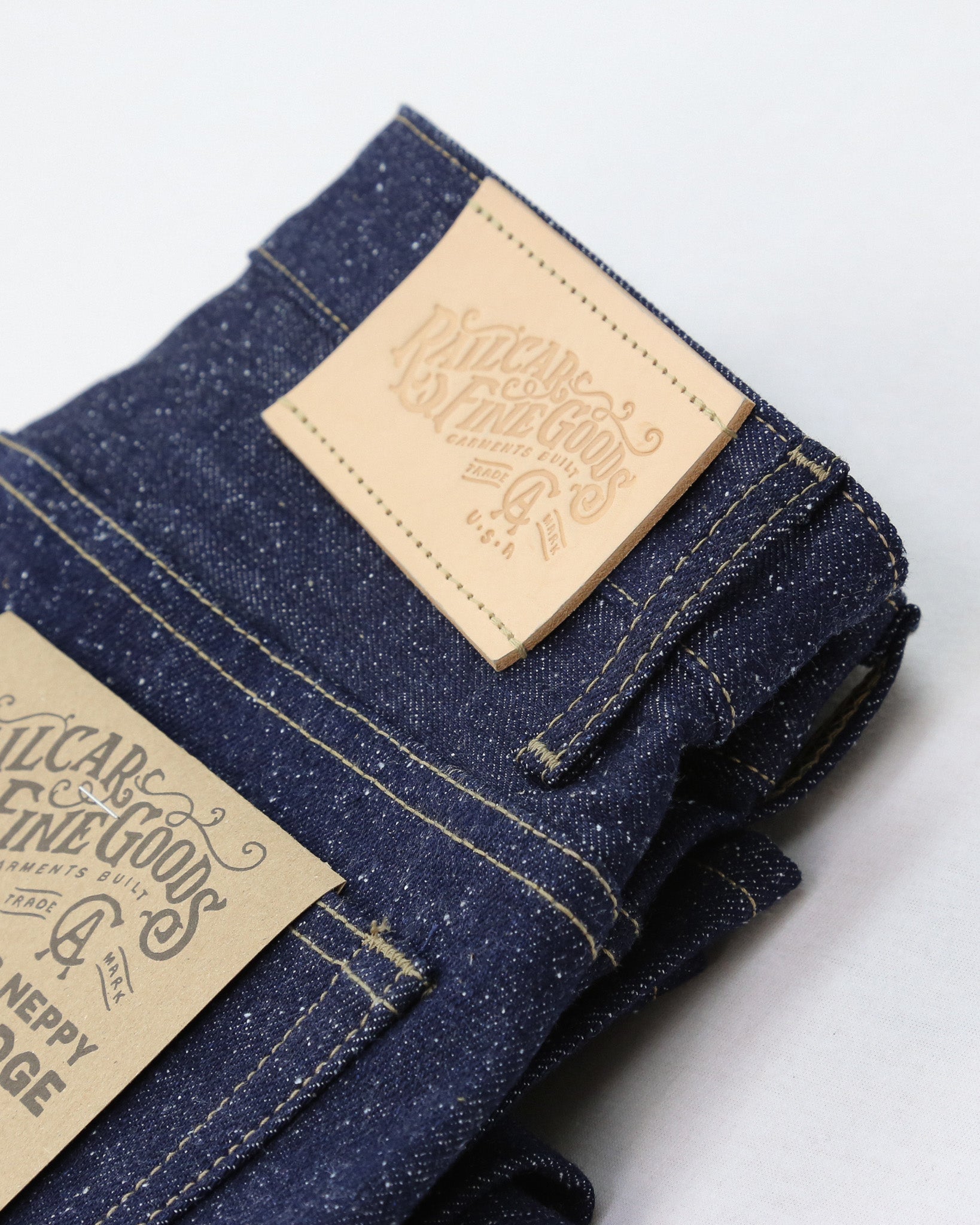 Folded denim jeans with a brand label on a light background