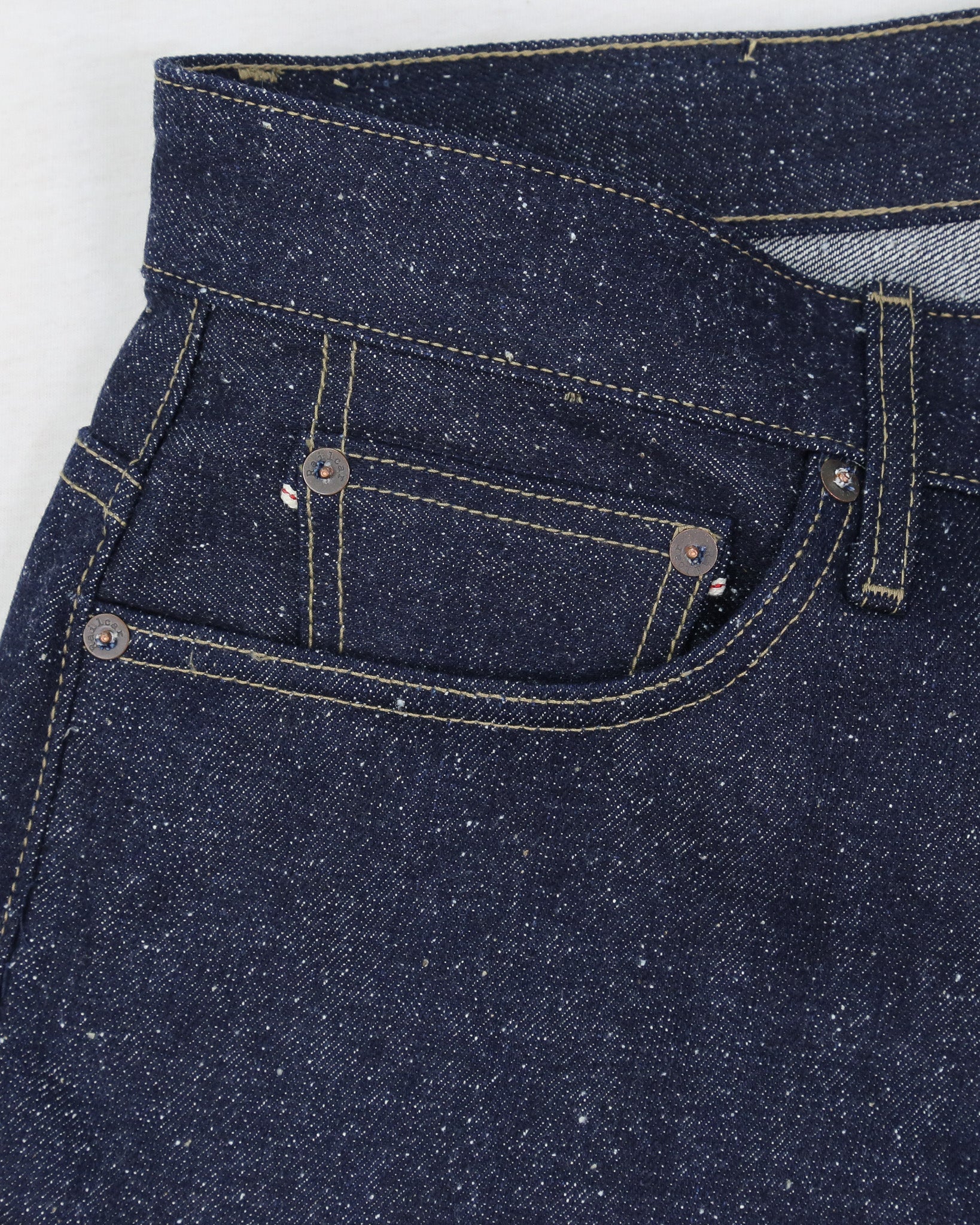 Close-up of dark blue denim jeans with stitching details on a white background