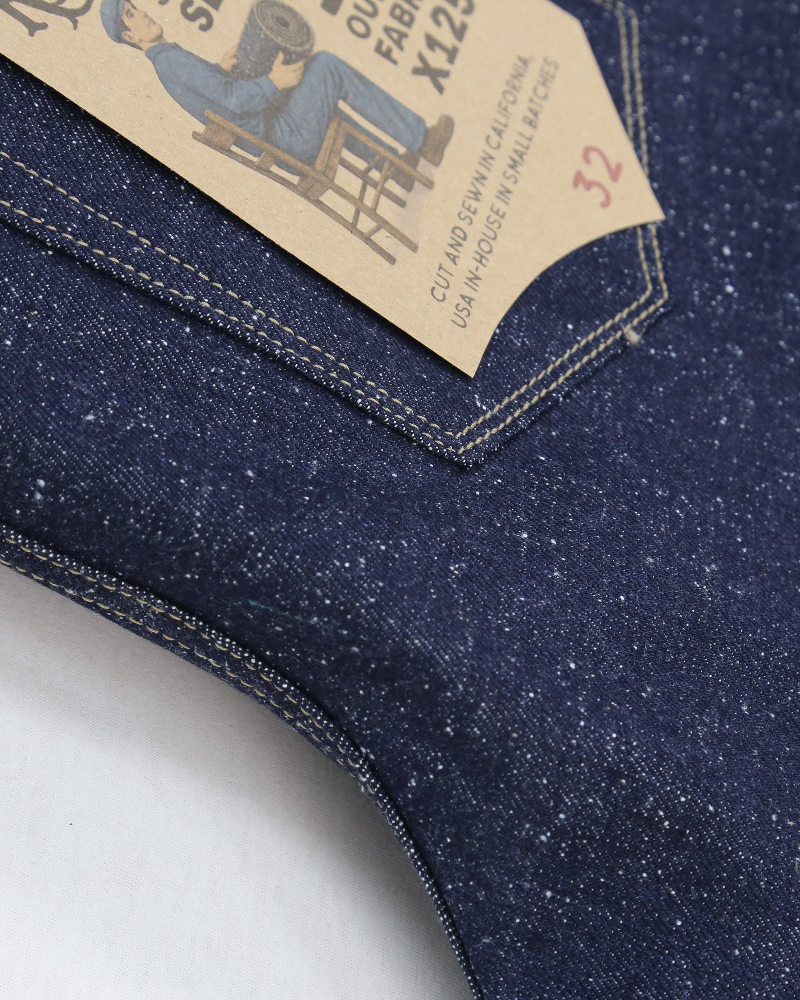 Close-up of blue denim fabric with a tag on a white background
